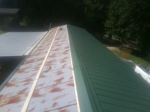 Old rusted panels beside newly installed green metal roofing — Wind Damage Roof Repair by Roofing Brothers in North Apollo