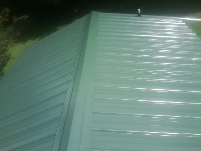 New green metal panels meeting at the ridge of a roof — Flat Roof Repair work by our crew in North Apollo