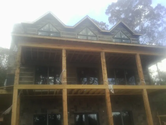 Dormers and porch framing on a large log home under construction — Roof Coating work by our crew in North Apollo