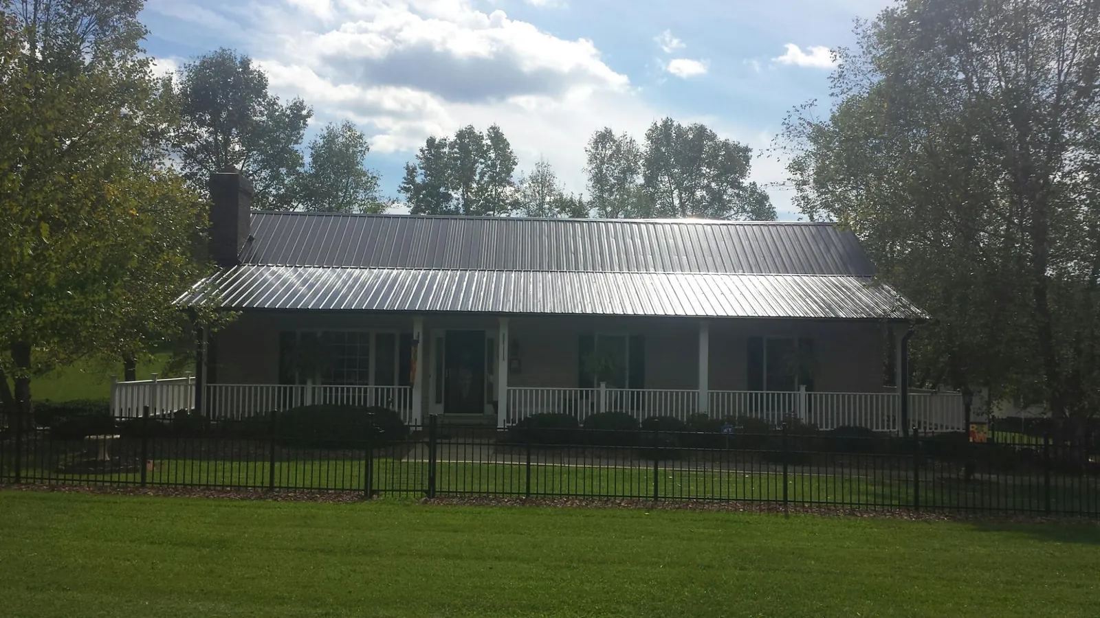Gray metal roof on a brick ranch with a full width front porch — Gutter Guard Installation work by our crew in North Apollo